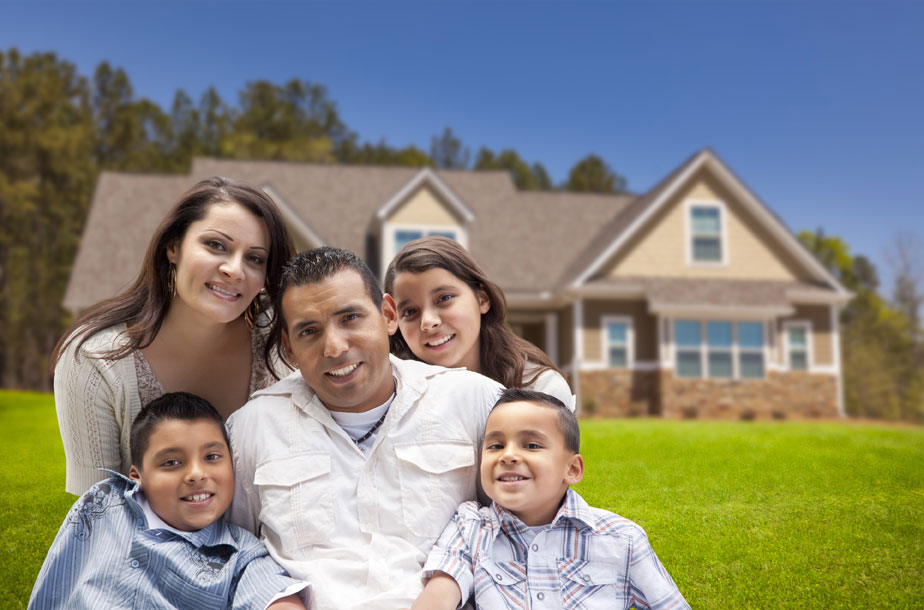 smiling family sitting on lawn in front of house